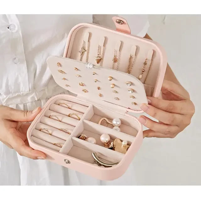 Boite a bijoux rose avec pleins de bijoux ranger présenter ouverte