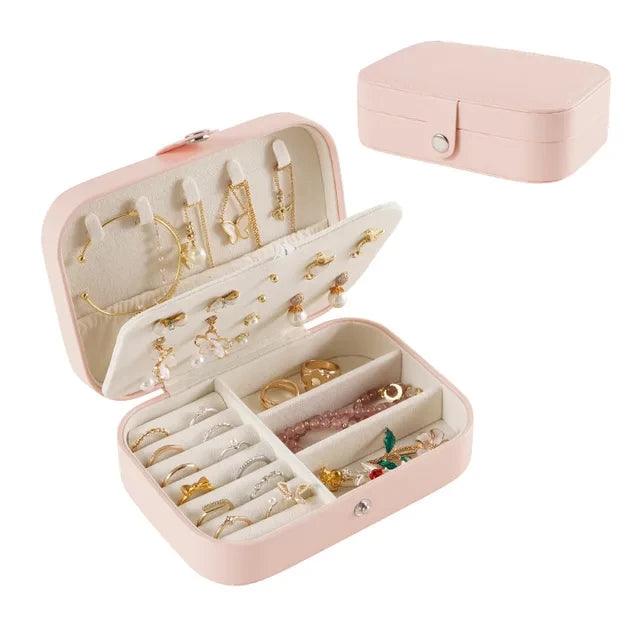 Boite a bijoux rose avec pleins de bijoux ranger avec derriere une boite a bijoux fermer