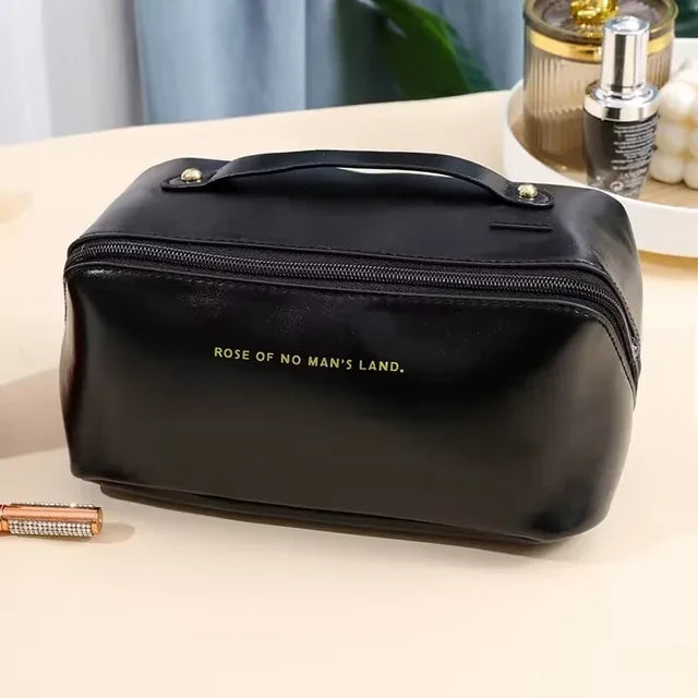 Trousse cosmétique transportable de voyage noire. Elle est présenter fermée et poser sur une coiffeuse