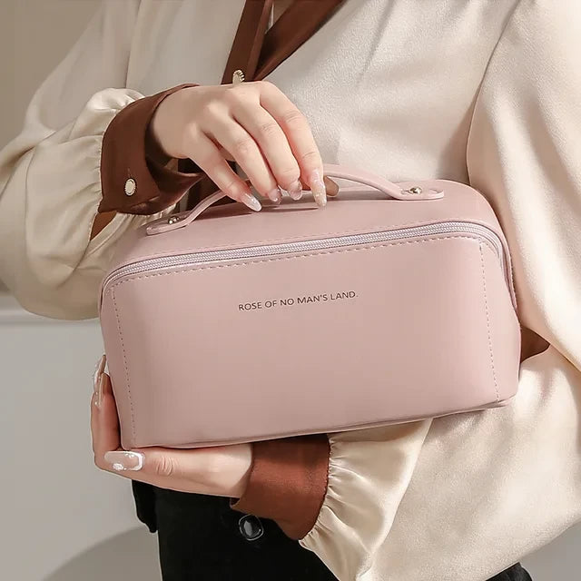 Trousse cosmétique pour voyage. Une femme transporte la trousse rose qui est fermée