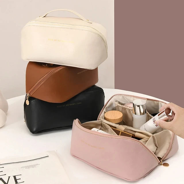 Trousse cosmétique portable de voyage. Les 4 couleurs posées sur une table. La noire, marron et blanche superposées et la rose posée a côté pleine de produits de maquillage et make-up