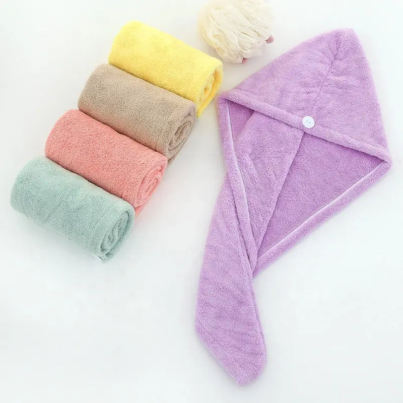 Serviette de séchage des cheveux. Une serviette mauve étalée et 4 pliées en rouleaux a coté. Jaune, marron, saumon et verte