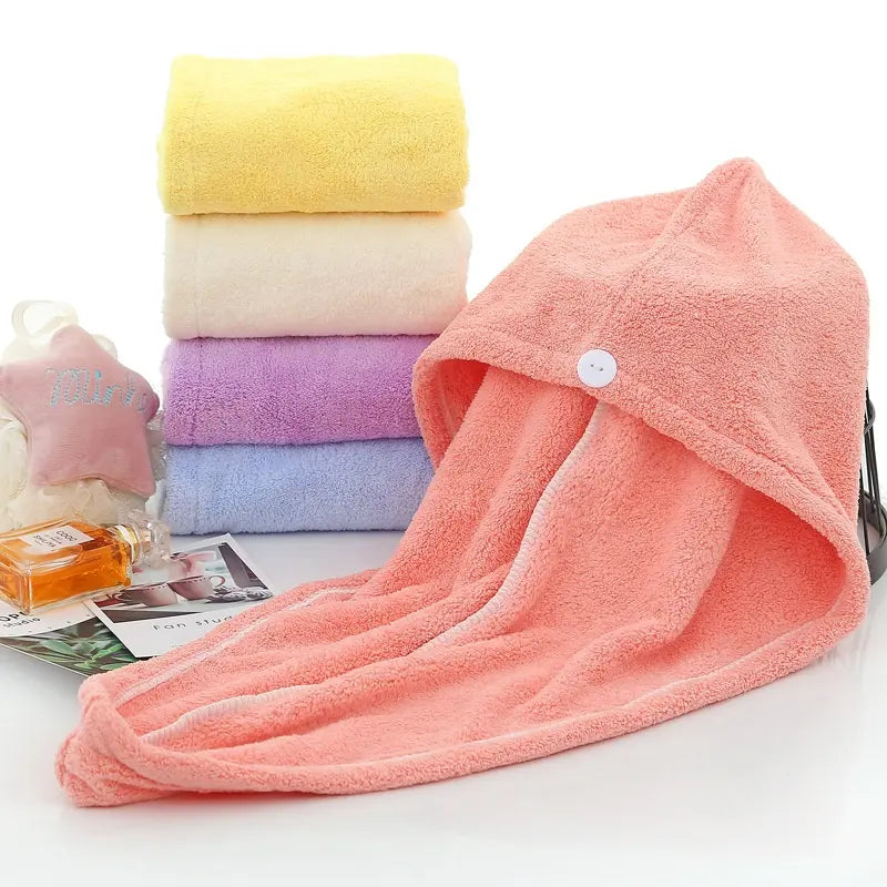 Serviette de séchage des cheveux. Une serviette couleur saumon étalée et 4 pliées en rouleaux a coté. Jaune, beige, mauve et bleue