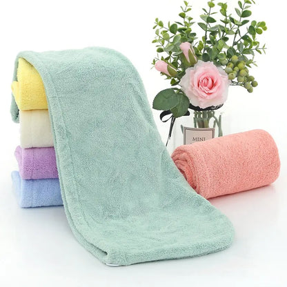 Serviette de séchage des cheveux. Une serviette verte étalée et 5 pliées en rouleaux a coté. Jaune, beige, mauve, bleue et saumon
