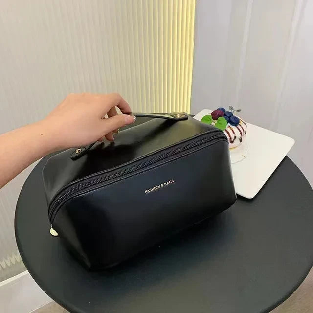 Trousse cosmétique de voyage noire. Femme qui la pose fermer sur une petite table